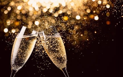 Two Glasses Of Champagne Toasting In The Night With Lights